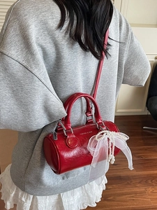 Sac seau cylindrique rouge chic en cuir brillant avec breloque noeud perle et anses de transport