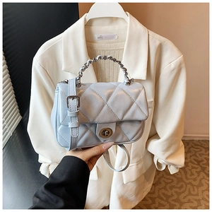 Detail of light blue quilted crossbody bag with metal chain handle and twist lock closure