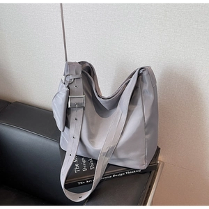 Detail of grey nylon shoulder bag with side coin pouch on a textured background