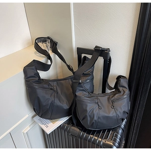 Detail of two black waterproof nylon crossbody bags in large and small sizes for travel