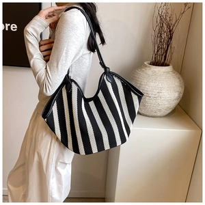 Model showing large black and white striped mesh tote bag with black leather shoulder strap