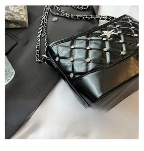 Close-up of quilted black leather texture with rhinestone star and metal chain strap