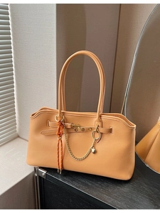 Retro light orange leather tote bag with chain strap and heart charm on display