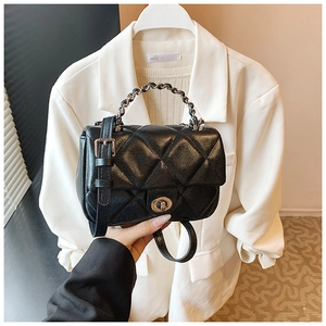 Close-up of black quilted leather crossbody bag featuring metal chain handle and twist lock