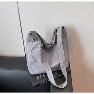 Detail of grey nylon slouchy tote bag with adjustable metal eyelet strap and small pouch