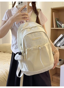 Detail of cream canvas backpack with star patterns and a cute panda plush charm