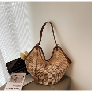 Close-up of woven straw tote bag with brown leather trim and handles in a cozy setting