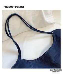 Detail of reinforced handles on a navy denim tote bag with contrast white stitching