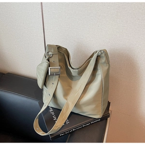 Macro shot of green nylon tote bag featuring wide shoulder strap and round coin purse