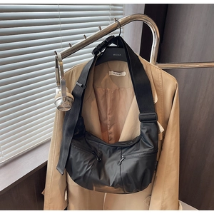 Detail of black nylon crossbody dumpling bag with wide adjustable strap and utility pockets