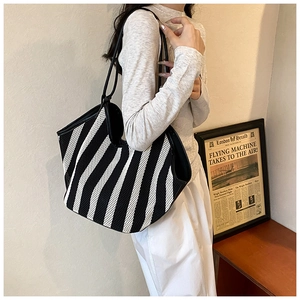 Detail of black and white striped mesh tote bag with leather straps on model's shoulder