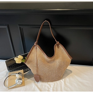 Détail d'un sac cabas en paille tressée avec bordure en cuir marron et accessoires