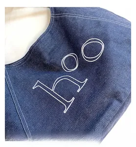 Detailed view of dark blue denim tote bag featuring white embroidered hOO letter branding