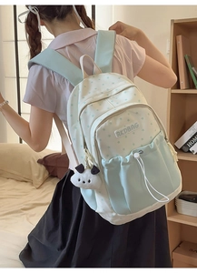 Detail of mint green student backpack with star pattern and cute plush dog pendant