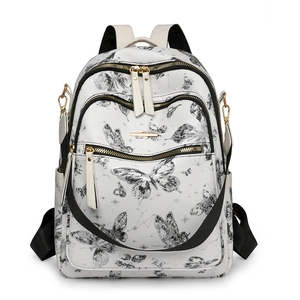 Détail du sac à dos en cuir blanc avec imprimé papillon noir et fermeture éclair dorée