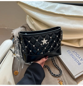 Detail of black quilted leather bucket bag with silver star studs and metal chain strap