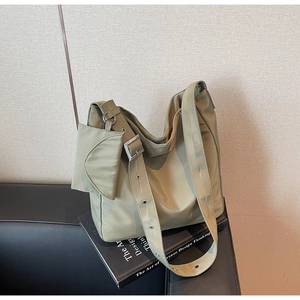 Detailed macro view of olive green nylon tote bag featuring wide strap with metal eyelets