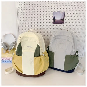 Detail view of water-resistant nylon backpack showing contrast panels and side drawstring pocket