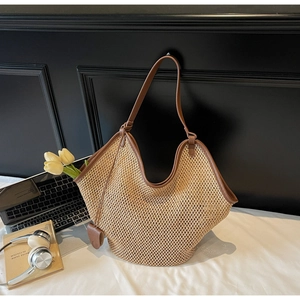 Détail du sac cabas en paille avec bordure en cuir marron et décor de bureau chic