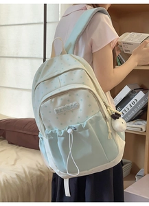 Detail of green star pattern school backpack with plush pendant and drawstring pocket