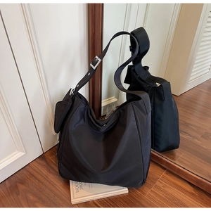 Detail view of black nylon shoulder bag with side pouch and adjustable silver metal buckle