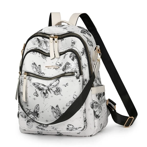 Détail du sac à dos blanc avec imprimés papillons noirs et fermetures éclair dorées