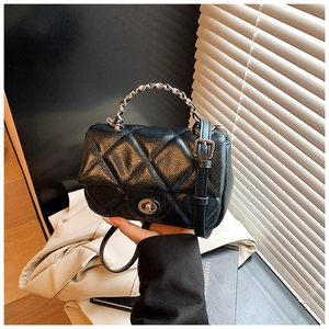 Detail of black quilted crossbody bag with silver twist lock and chain handle