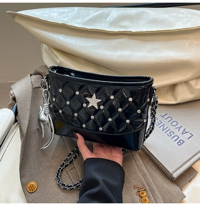 Detail of black quilted chain bag with silver star rivets and cat charm pendant