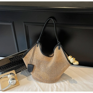 Détail du sac cabas en paille tressée avec anses et pochette en cuir noir
