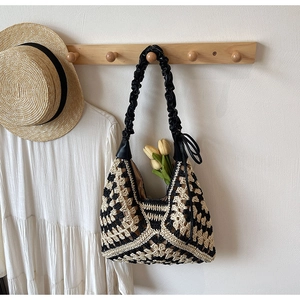 Close-up of a handmade crochet hobo bag with black and white patterns and leather strap