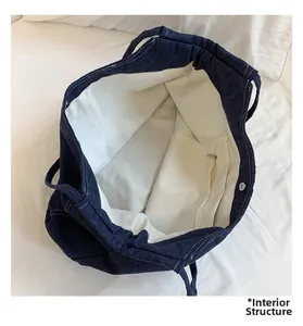 Detail view of denim tote bag interior with beige canvas lining and zipper pocket