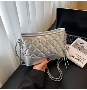 Detail of silver quilted bucket bag with star rhinestone ornament and metal chain strap