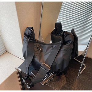 Detail of black nylon tote bag featuring adjustable shoulder strap and zip functional pockets