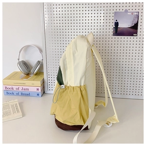 Detail of backpack side with yellow drawstring pocket and contrasting brown bottom panel