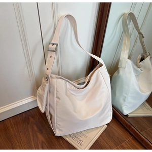 Detail of minimalist cream tote bag with adjustable strap and mini pouch charm