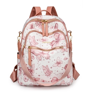 Détails d'un sac à dos blanc avec imprimés papillons et fermetures éclair dorées