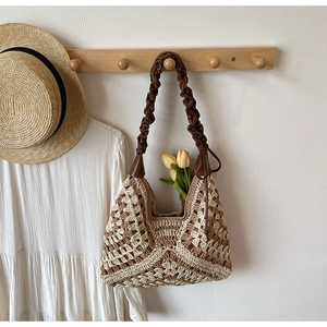 Detail view of woven crochet texture and ruched brown leather strap on a summer beach bag