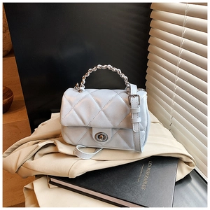 Detail of light blue quilted crossbody bag with silver chain handle on office blazer