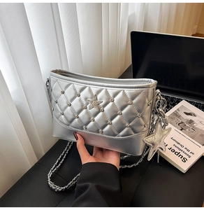 Detail of silver quilted crossbody bag with rhinestone star charm and metal chain