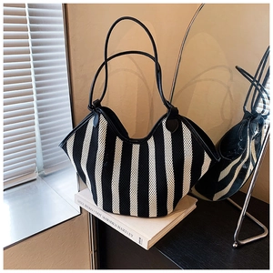 Detail of black and white striped knit tote bag with elegant leather shoulder straps