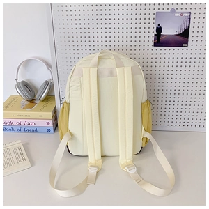 Detail view of the yellow backpack featuring elastic side pockets and padded shoulder straps