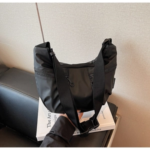 Detail view of black nylon hobo bag with multi-zipper pockets and wide webbing strap