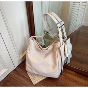 Close-up of beige nylon hobo bag with a matching mini coin purse on a wooden floor