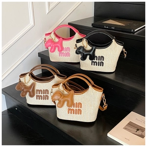 Detail view of woven straw basket handbags in four colors with cute dog charms