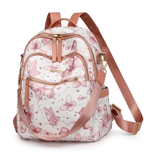 Détail d'un sac à dos blanc avec motifs papillons roses et fermetures éclair dorées