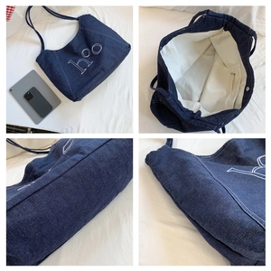 Detail view of denim tote bag showing interior lining, magnetic snap and hoo embroidery