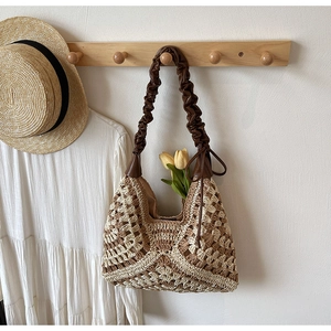 Detail of hand-woven straw shoulder bag with brown leather strap and floral decor