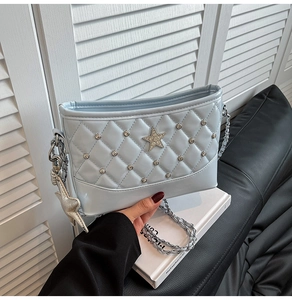 Detail of light blue quilted bucket bag featuring a silver star pendant and chain strap