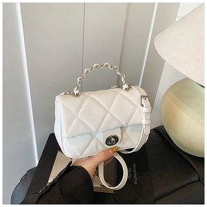 Detailed shot of white quilted crossbody bag with silver chain handle and turn-lock