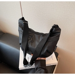 Detailed close-up of a black nylon crescent bag with adjustable strap and zip pocket
